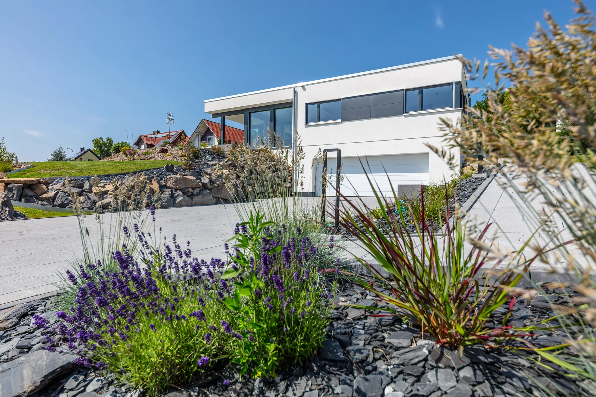 Bungalow Fusion am Hang mit Keller und Doppelgarage von Meisterstueck Haus aus Vorderansicht mit Blumen